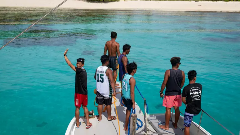 Group standing on a boat above clear tropical reef water